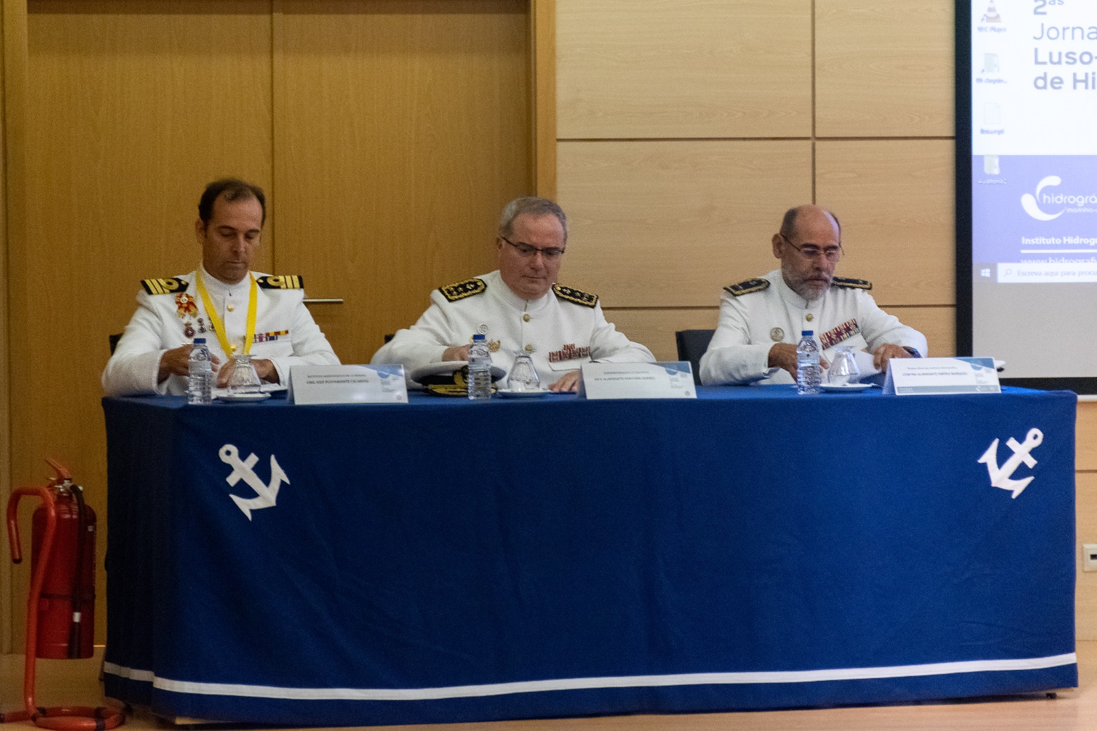 Dois militares da Marinha Portuguesa e um da Marinha espanhola sentados à mesa